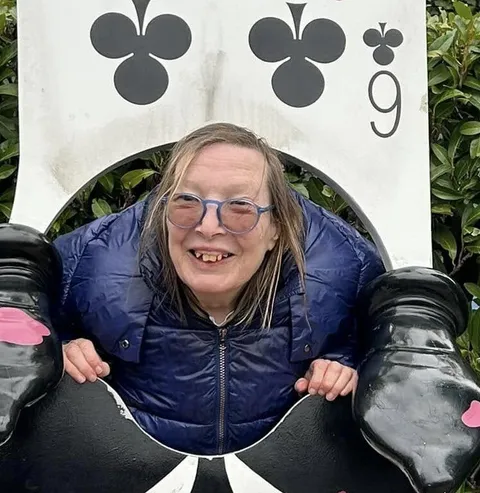 A holidaymaker smiling through a giant playing-card photo cutout