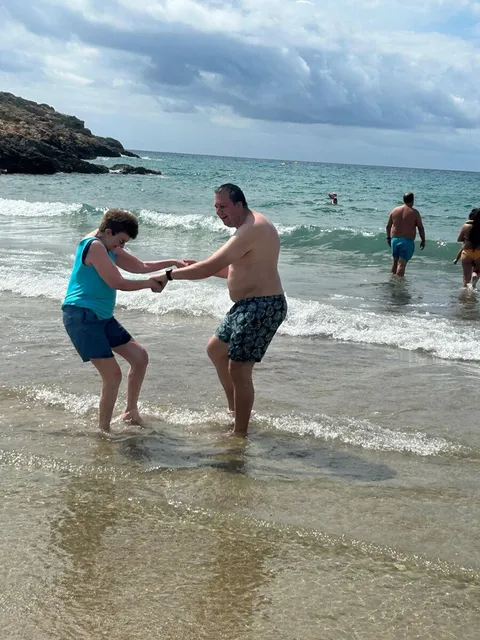 Two holidaymakers paddling hand in hand at the water's edge